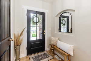 Foyer featuring healthy amount of natural light, light wood-type flooring, and arched walkways