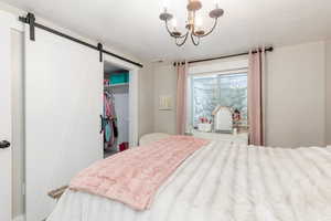 Bedroom with a barn door, a closet, a walk in closet, and a chandelier