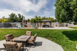Fenced backyard with a patio area, an outdoor hangout area, a shed, a playground, and a trampoline