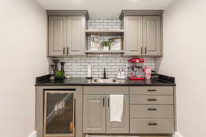 Indoor wet bar featuring wine cooler and decorative backsplash