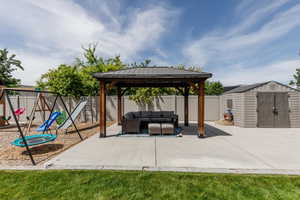 Fenced backyard featuring outdoor lounge area, a playground, a gazebo, a patio, and a storage shed