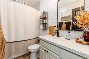 Full bath featuring vanity, wood finished floors, wood walls, and a shower with shower curtain