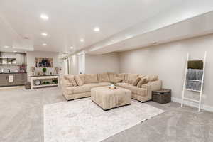 Living room with light colored carpet, recessed lighting, and bar