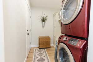 Washroom featuring stacked washer / dryer, light wood-type flooring, and cabinet space