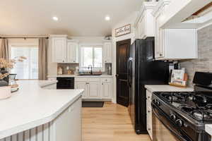 Kitchen featuring gas range, dishwasher, light countertops, light wood-type flooring, and recessed lighting