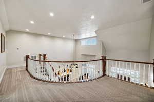 Hallway featuring carpet floors, recessed lighting, an upstairs landing, and lofted ceiling