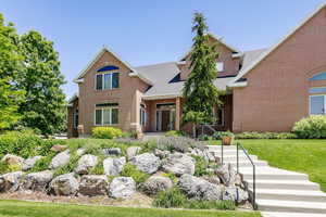 View of front of house with brick siding, a shingled roof, and a front yard