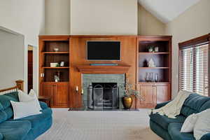 Carpeted living area featuring high vaulted ceiling and a high end fireplace