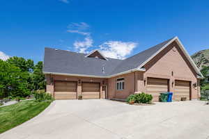 View of front facade with brick siding, a garage, driveway, and a front yard