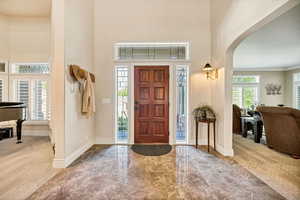 Foyer entrance with arched walkways, a high ceiling, carpet floors, marble finish flooring, and crown molding