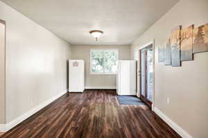 Unfurnished room with dark wood finished floors and a textured ceiling