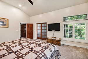Carpeted bedroom featuring french doors, high vaulted ceiling, and ceiling fan