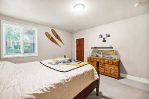 Carpeted bedroom with a textured ceiling and baseboards