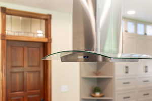 Kitchen view of island exhaust hood and white cabinets