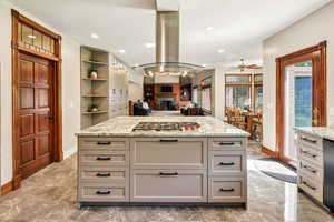 Kitchen featuring stainless steel gas stovetop, ceiling fan, island range hood, marble tiled floors, and gray cabinetry