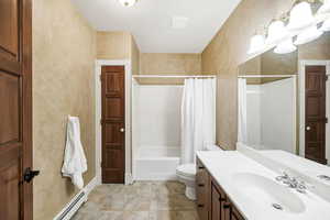 Bathroom with shower / bath combo, vanity, tile patterned flooring, and a baseboard heating unit