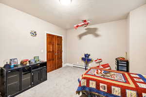 Carpeted bedroom featuring baseboard heating and a textured ceiling