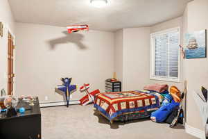 Bedroom with baseboard heating, carpet, and a textured ceiling