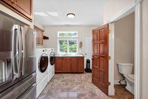 Washroom featuring washer and clothes dryer, marble finish flooring, and cabinet space