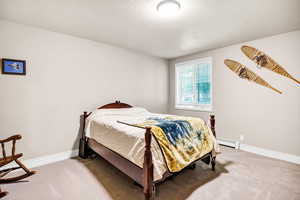 Carpeted bedroom with a baseboard radiator and a textured ceiling