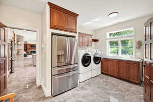 Washroom with washing machine and clothes dryer, light marble finish floors, and cabinet space