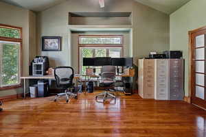 Office space featuring vaulted ceiling, wood finished floors, and plenty of natural light