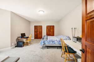Bedroom with a desk, carpet flooring, and multiple closets