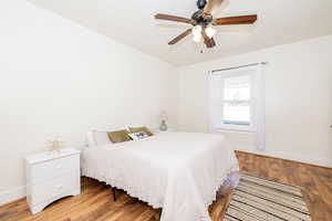 Bedroom with wood finished floors, ceiling fan, and a textured ceiling