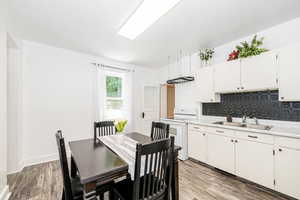 Kitchen with electric range, tasteful backsplash, light countertops, and light wood finished floors