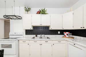 Kitchen with white appliances, light countertops, and backsplash