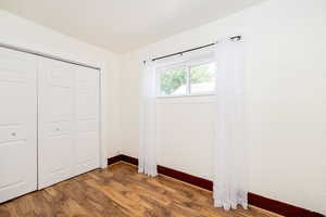Unfurnished bedroom with wood finished floors and a closet