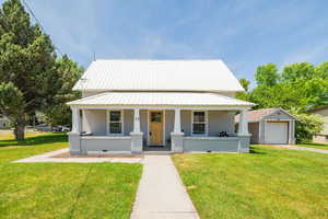 View of front of home with covered porch, a metal roof, and a front lawn