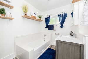 Bathroom with a bath, vanity, and wood finished floors