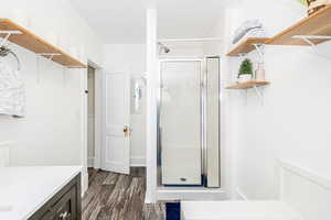 Bathroom with a shower stall, wood finished floors, vanity, and electric panel