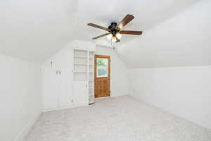 Additional living space featuring lofted ceiling, ceiling fan, and light carpet