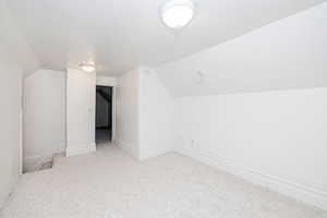 Bonus room featuring vaulted ceiling and carpet floors