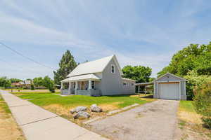 View of front of house with a front lawn, a garage, an outbuilding, and driveway