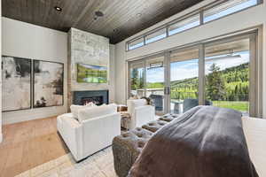 Bedroom featuring access to outside, a fireplace, wood ceiling, recessed lighting, and light wood-type flooring