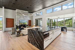 Kitchen with stainless steel microwave, modern cabinets, a kitchen island with sink, white cabinets, and dark stone countertops