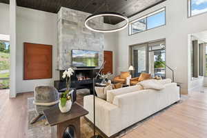 Living area featuring a towering ceiling, wood ceiling, wood-type flooring, and a high end fireplace