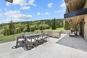 View of patio with a forest view and outdoor dining area