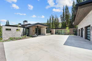 View of front of home with stone siding, a chimney, and concrete driveway
