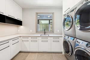Laundry area featuring stacked washer / dryer, cabinet space, and light tile patterned floors