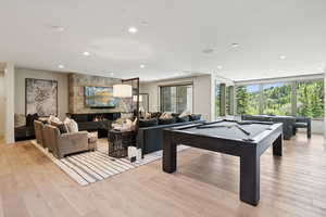 Playroom featuring billiards, light wood-type flooring, a stone fireplace, and recessed lighting