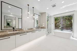 Bathroom featuring double vanity, a freestanding tub, a stall shower, recessed lighting, and tile patterned floors