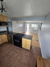 Kitchen featuring black appliances, dark countertops, light brown cabinets, and dark tile patterned floors