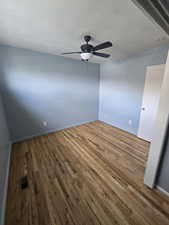 Empty room with a ceiling fan and hardwood / wood-style flooring