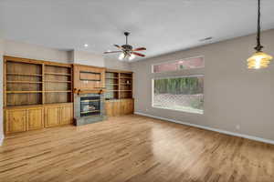 Unfurnished living room with light wood finished floors, a tiled fireplace, ceiling fan, and recessed lighting
