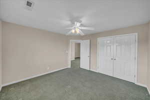 Unfurnished bedroom featuring carpet, a closet, and a ceiling fan