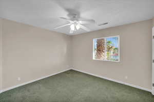 Empty room featuring dark carpet and ceiling fan